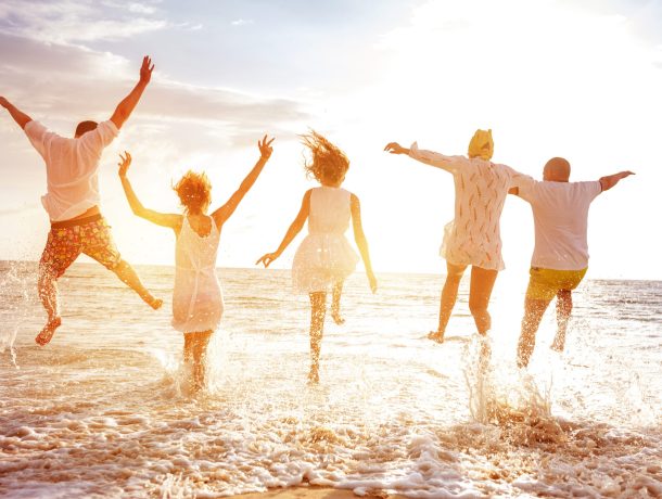 Group of five peoples run and jump to sunset sea